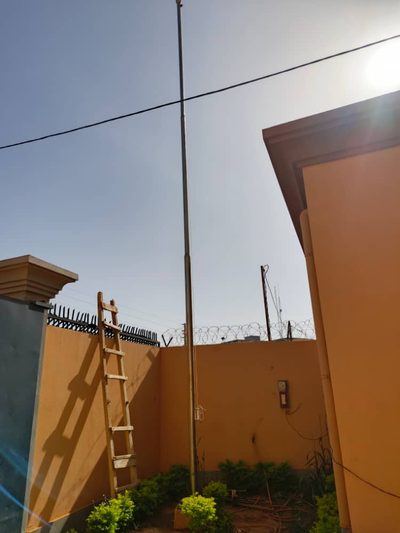 Pose du mât porte-drapeau contre le mur d'enceinte de l'ambassade de Mauritanie, échelle en appui